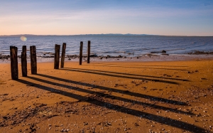 Sombras de pilares de madera sobre playa arenosa